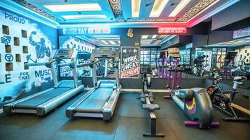 Un gimnasio con cintas de correr, elípticas y equipo de pesas.