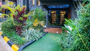 Un bâtiment moderne doté d’un jardin bien entretenu, où l’on trouve diverses plantes et une pelouse soigneusement taillée.