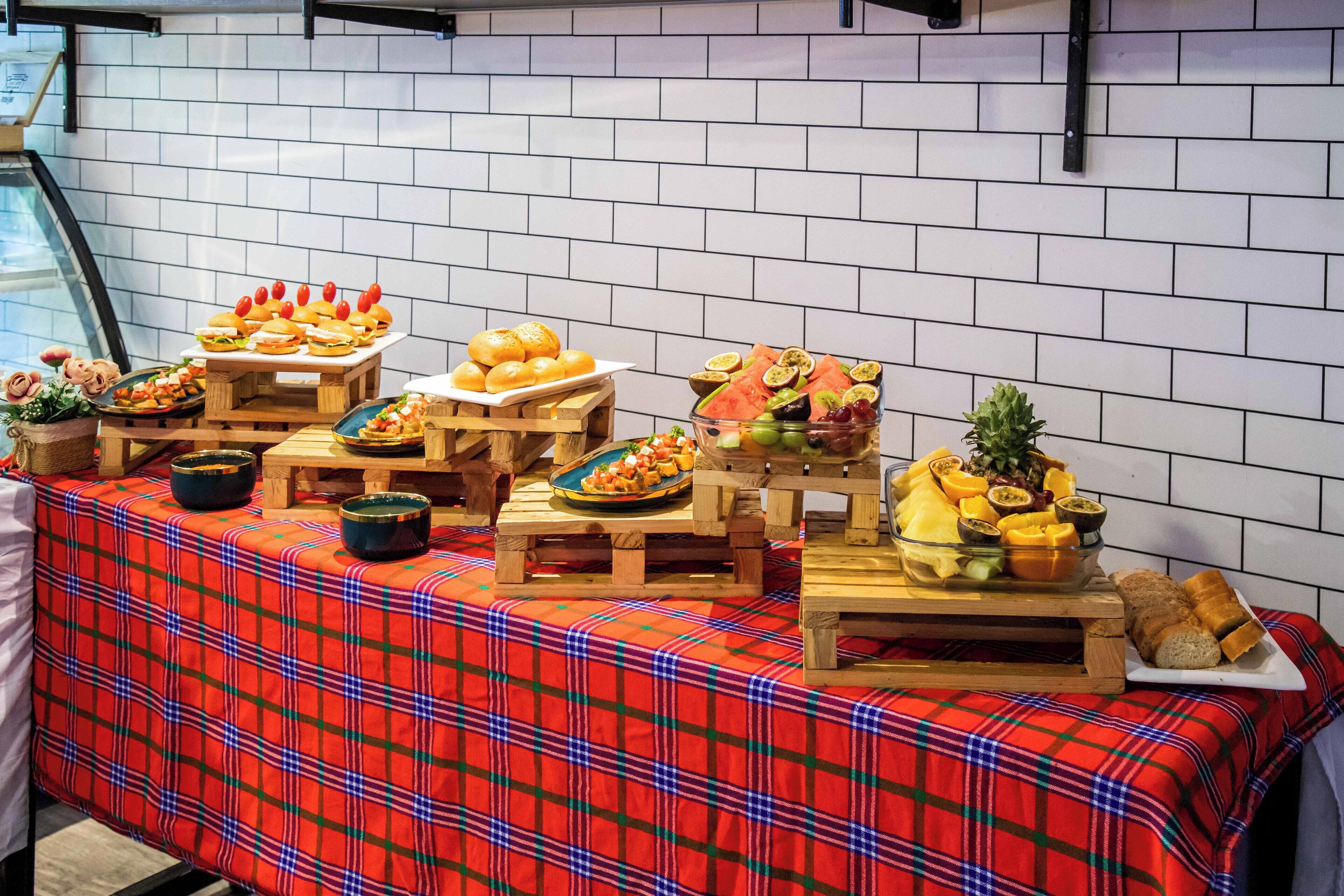 A buffet table with various food items and a red plaid tablecloth.