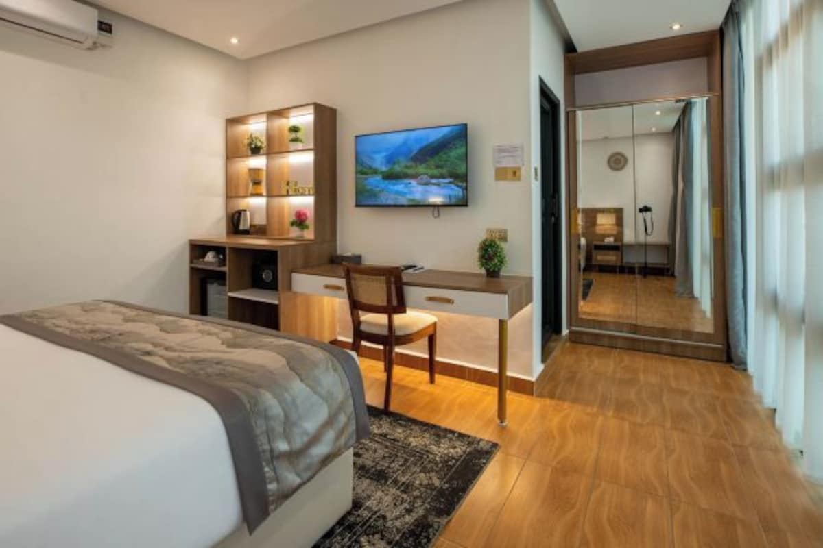 A hotel room with a bed, desk, chair, TV, and a mirror.