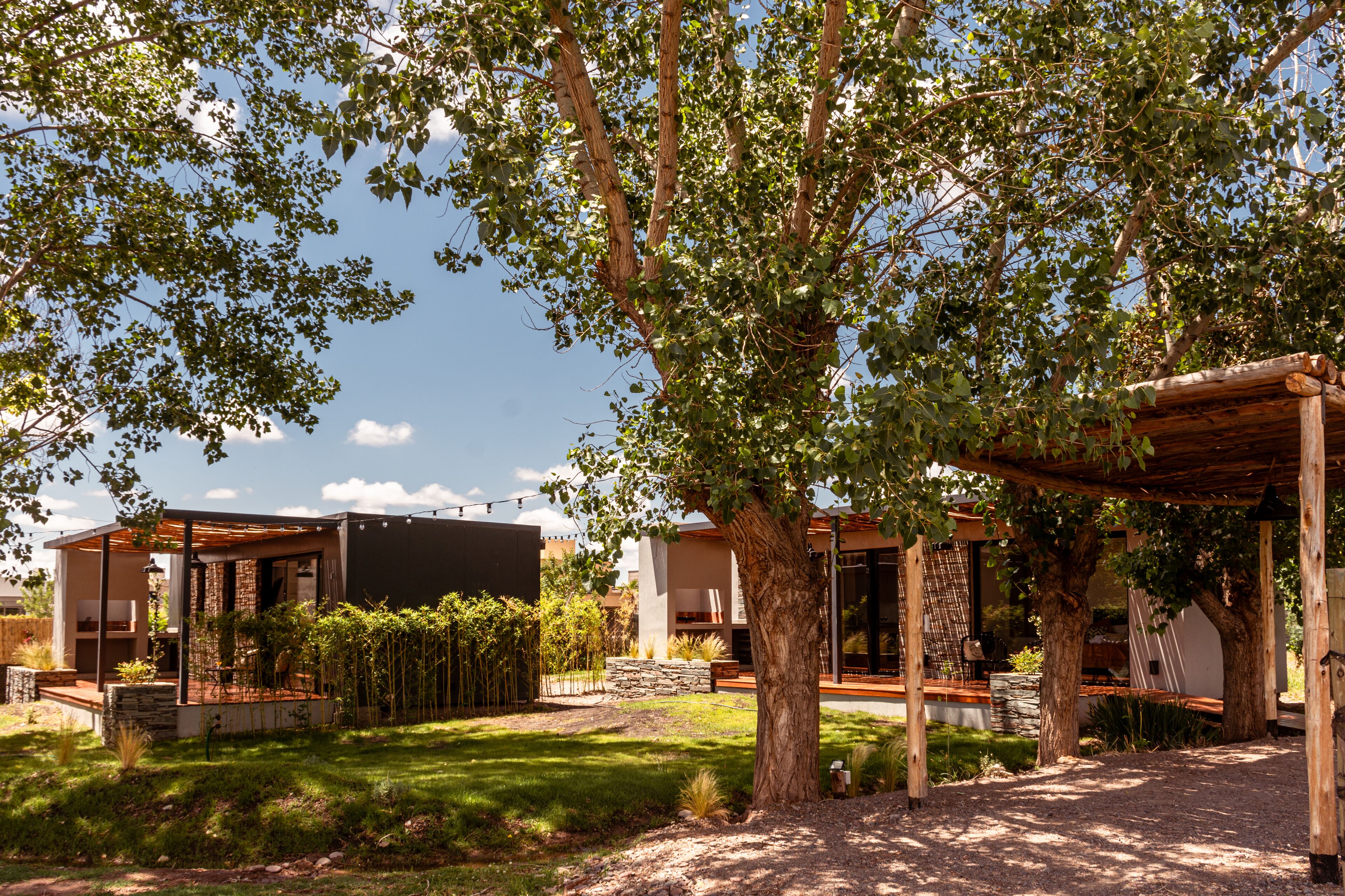 Une maison moderne dotée d’un patio couvert, d’un mur en pierre et d’un jardin bien entretenu.