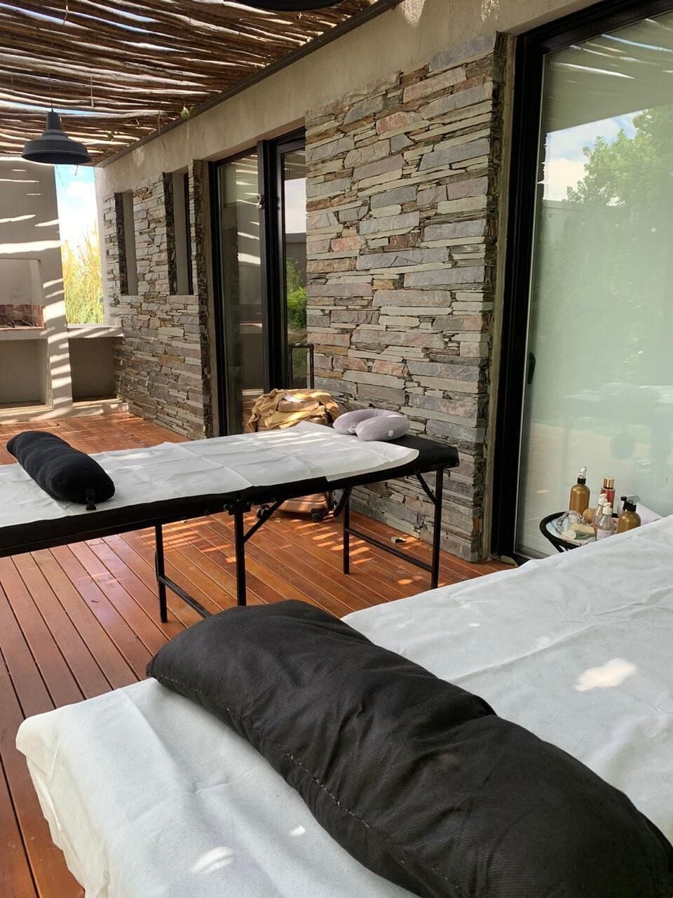 A spa area with wooden flooring, stone walls, and two massage tables with towels and pillows.
