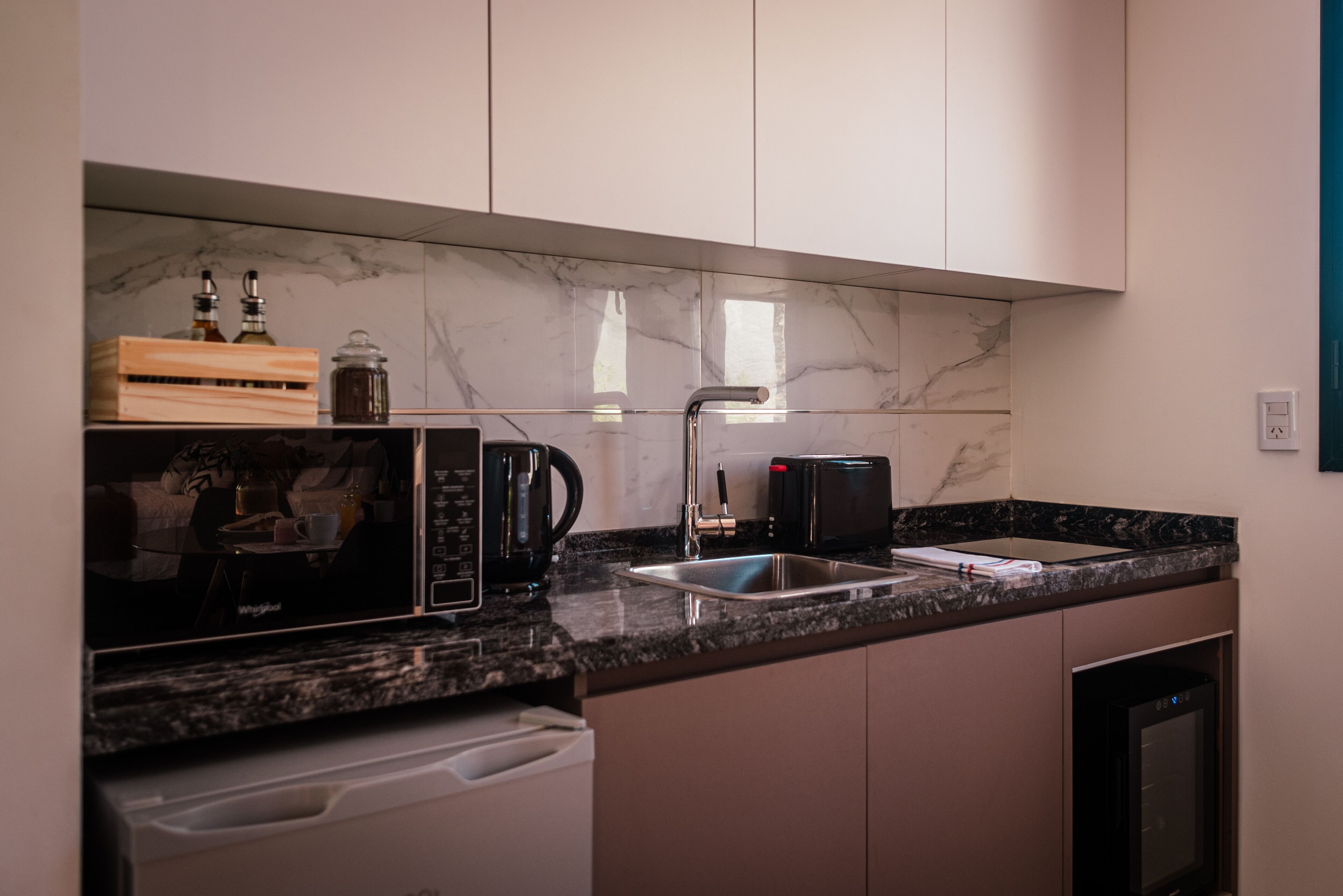 Een moderne keuken met een ingebouwde magnetron, koffiezetapparaat en spoelbak.