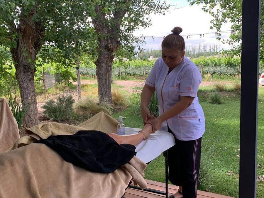 A person performing a massage on another individual seated on a wooden deck.