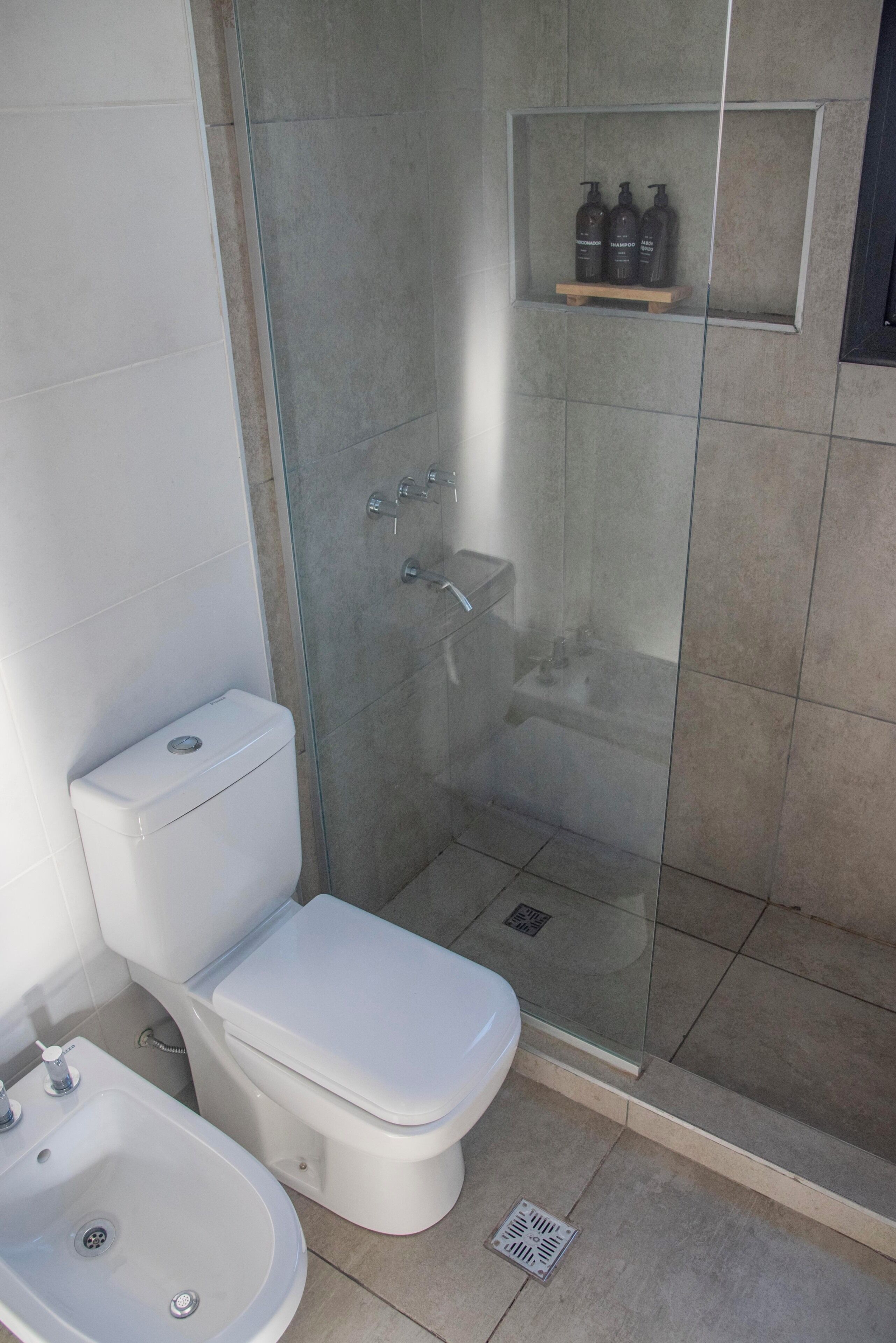 Une salle de bain moderne équipée de toilettes, d’un bidet et d’une douche séparée par des parois en verre.