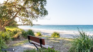 A bench by a beach with clear skies and calm waters. - Coastal Escape – waterfront reserve on Jervis Bay (Vincentia)