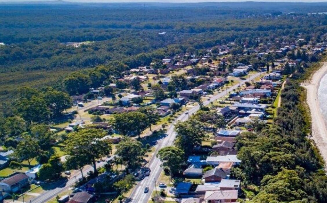 An aerial view of a residential area with houses, roads, and a beach.