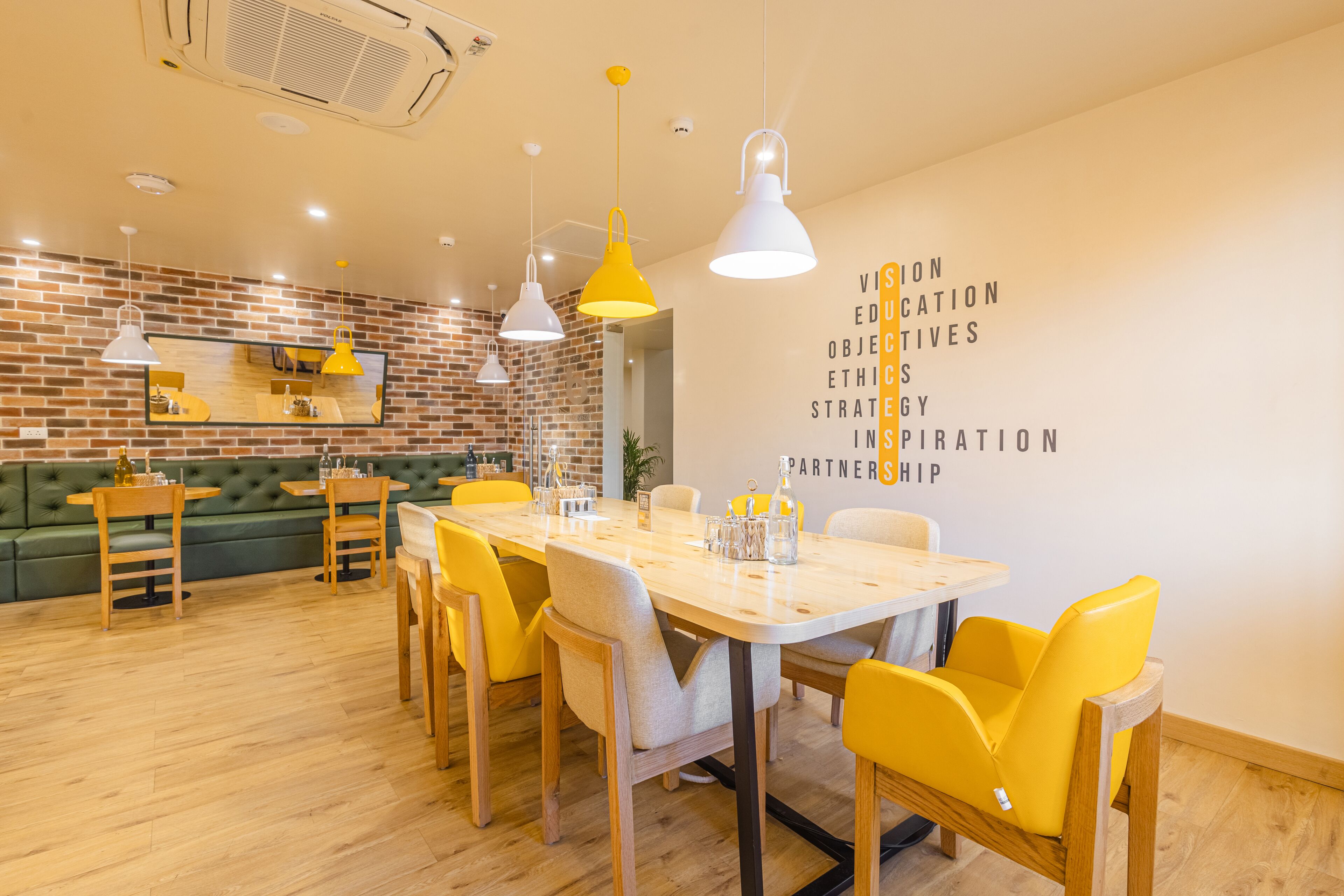 A modern dining area with a wooden table, yellow chairs, and pendant lighting.