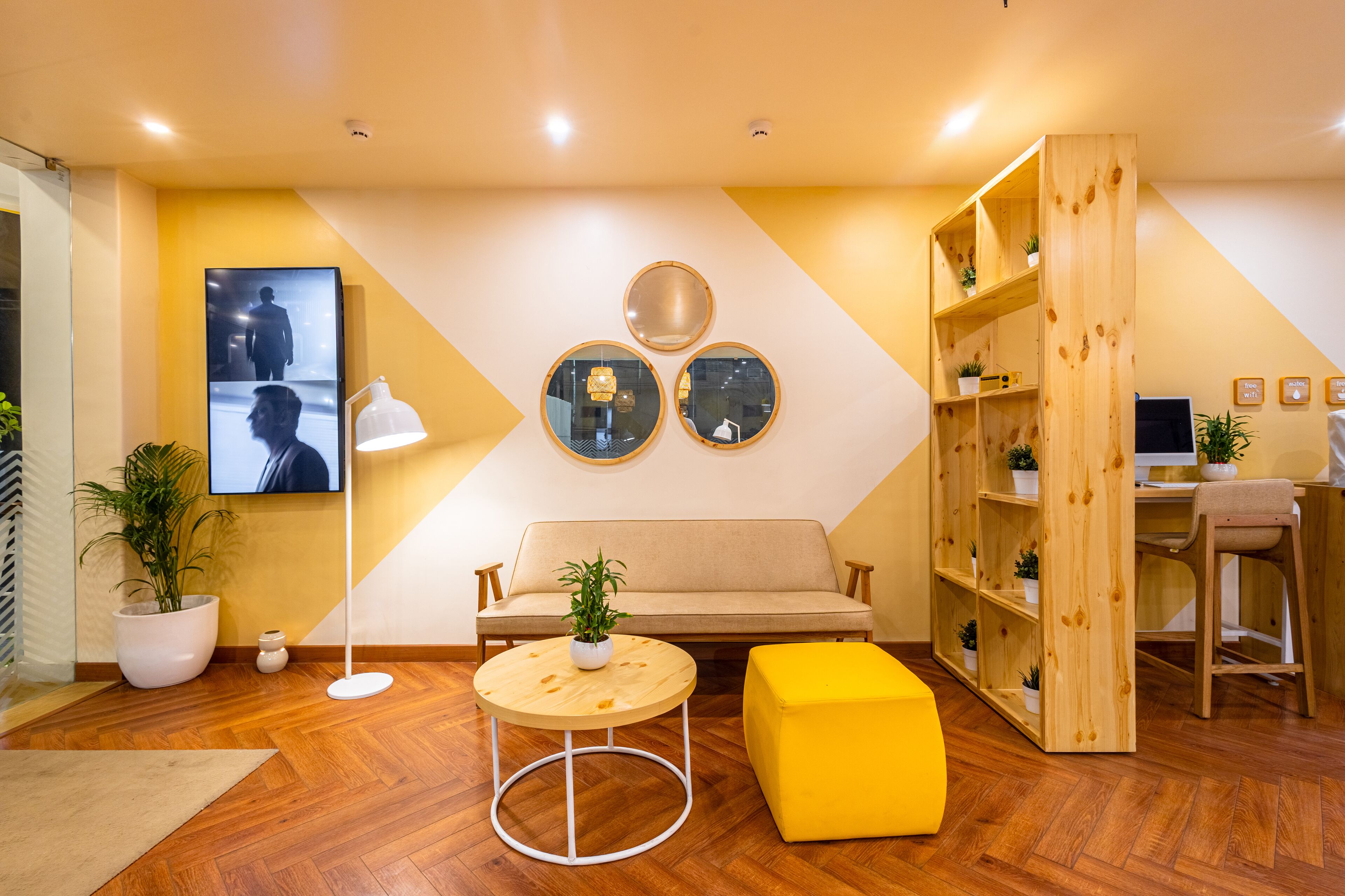 A modern interior with a sofa, round table, and wooden shelving unit.