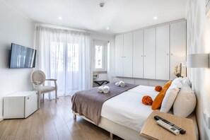 A hotel room with a bed, a desk, a chair, a TV, and a wardrobe. - Lisbon Terrace Suites for Large Groups (Lisbon)