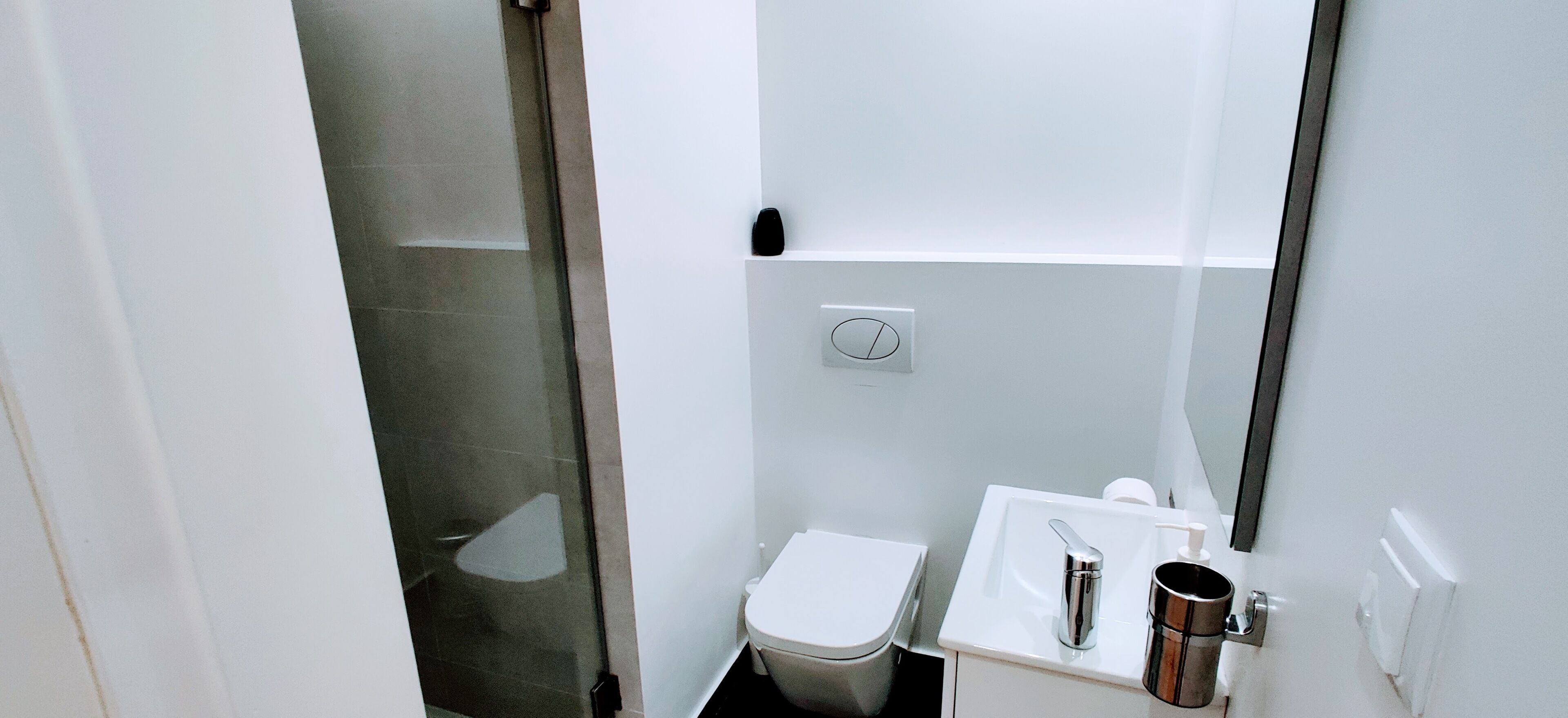 Un bany petit i modern amb vàter, rentatge i plat de dutxa.