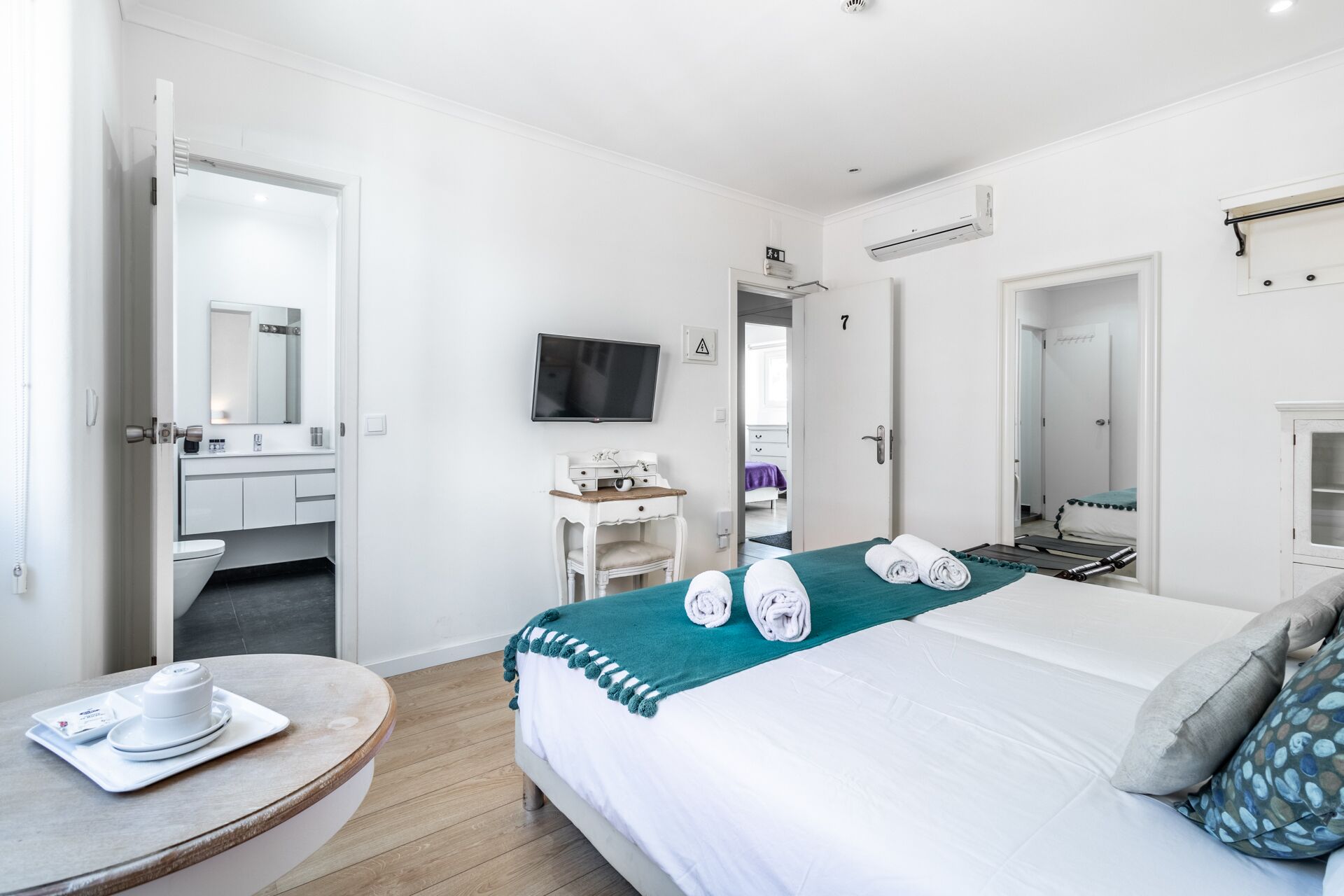 Una habitación de hotel con cama, escritorio, televisor, baño y área de comedor.