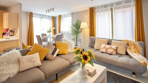 Un salon moderne avec un canapé, une table basse et, au fond, un coin repas.