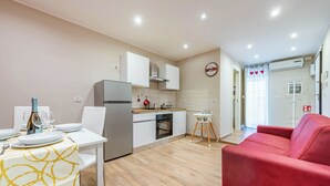 A modern kitchen with white cabinets, a built-in oven, and a dining area with a white table and yellow patterned tablecloth. - Levante Home in the Centre of Bari (Bari)