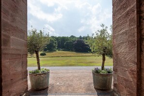 An open doorway with two potted trees and a view of a grassy field and trees in the distance. - Birch Cottage - sleeping 6 guests in 3 bedrooms (Cockburnspath)