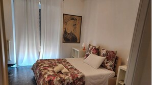 A bedroom with a bed, a nightstand, a lamp, and a painting on the wall. - Direct connection to the city center. Comfortable apartment in the green. (Roma)