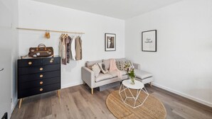 A minimalist room with a black dresser, a grey sofa, a round coffee table, and a woven rug. - Business Flat in Little Tokyo (Düsseldorf)