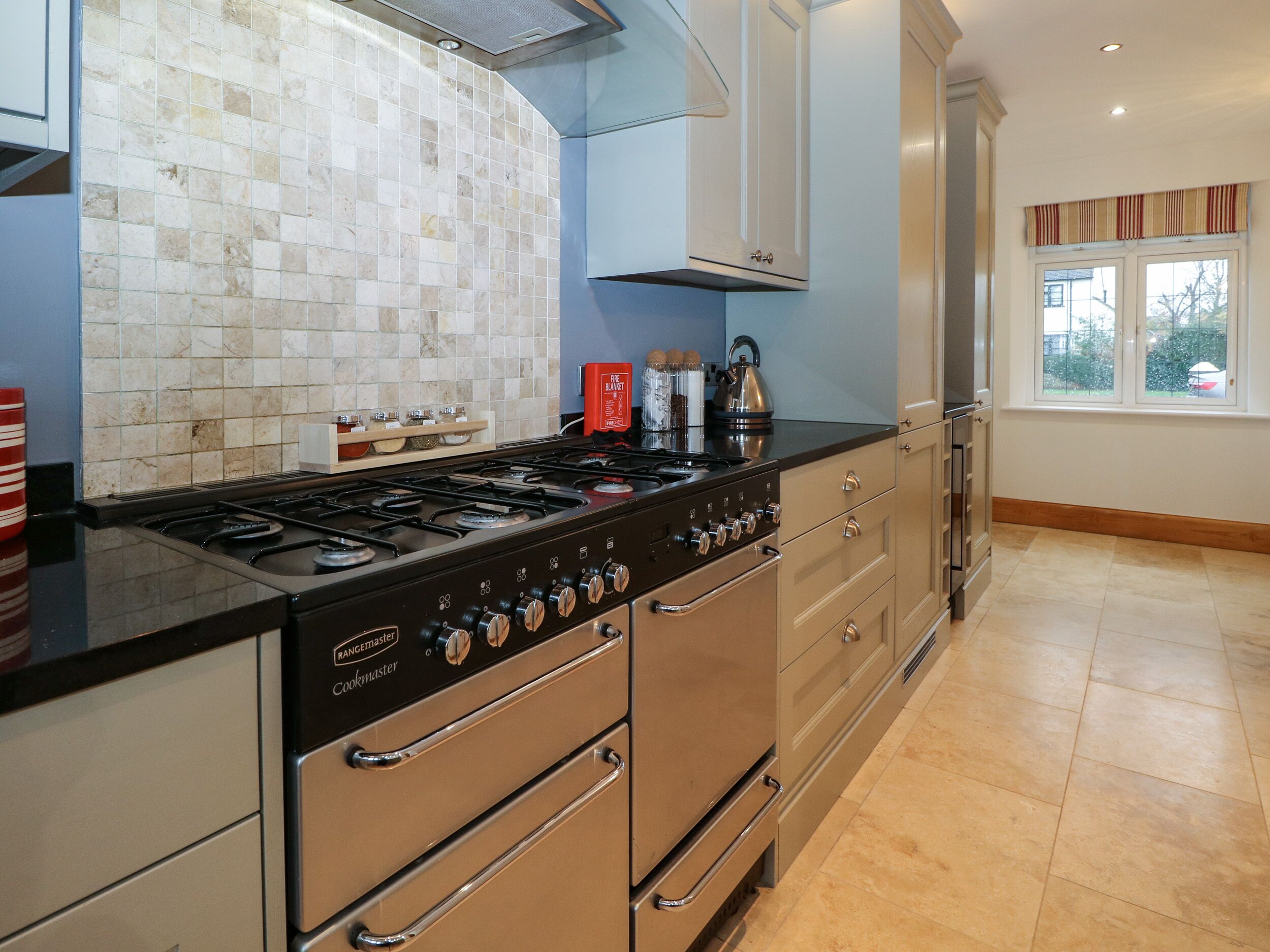 Cozinha moderna com fogão a gás, eletrodomésticos em aço inoxidável e painel de azulejos.