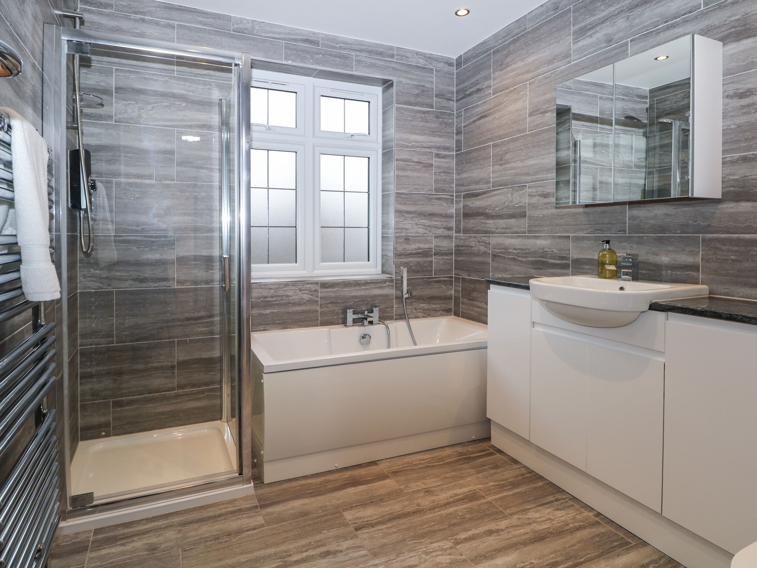 A modern bathroom with a glass-enclosed shower, a freestanding bathtub, and a vanity with a sink and mirror.