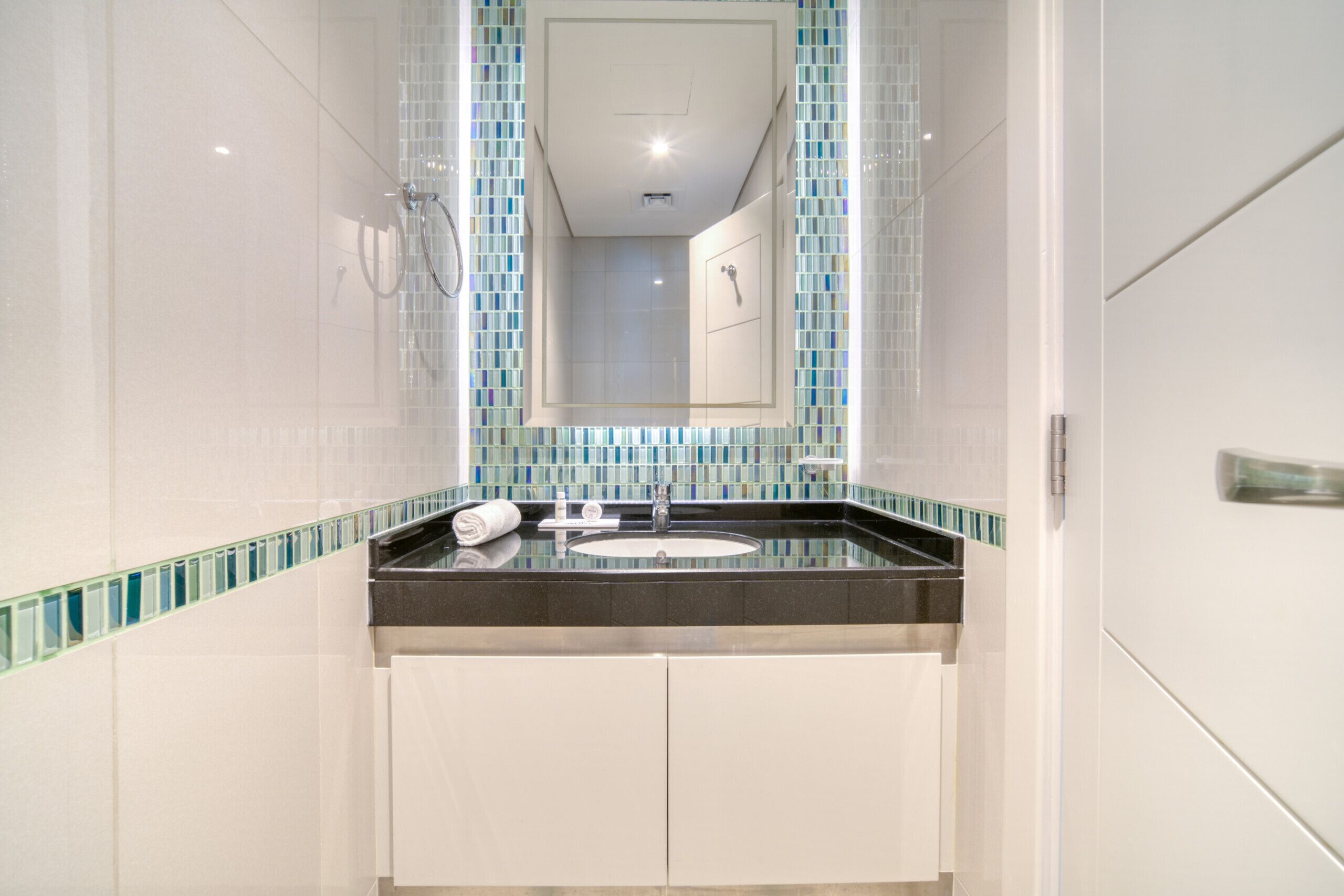 A modern bathroom with a glass-enclosed shower, a sink with a mirror above, and white cabinets.