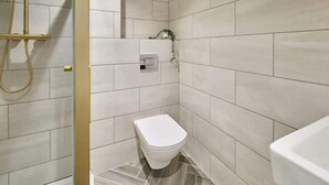 Une salle de bain moderne équipée de toilettes, d’une douche et d’un lavabo.