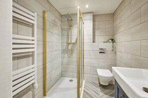 Un baño moderno con ducha a ras de suelo, inodoro y zona de lavamanos.
