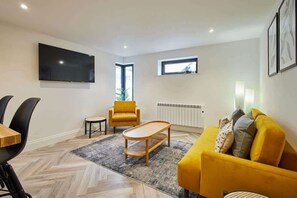 Una sala de estar moderna con un sofá, una mesa de centro, un televisor y una silla.