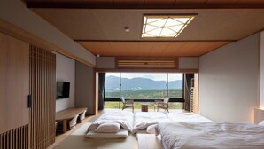 A modern hotel room with a large bed, a TV, a dining area, and a view of mountains. - Hakone Ashinoko Bikeikan (Hakone)
