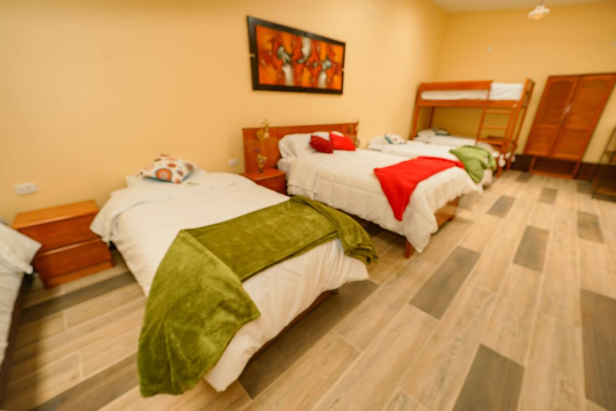 A hotel room with two beds, a wooden wardrobe, and a painting on the wall.
