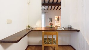 Um quarto com uma mesa de jantar de madeira, uma cadeira, um interruptor de luz e um quadro pendurado na parede.