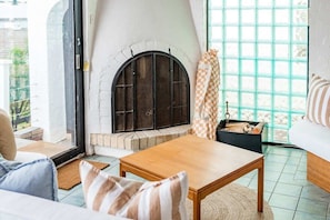 Een gezellige woonkamer met een open haard, een bank, een bijzettafeltje en een groot raam met uitzicht.