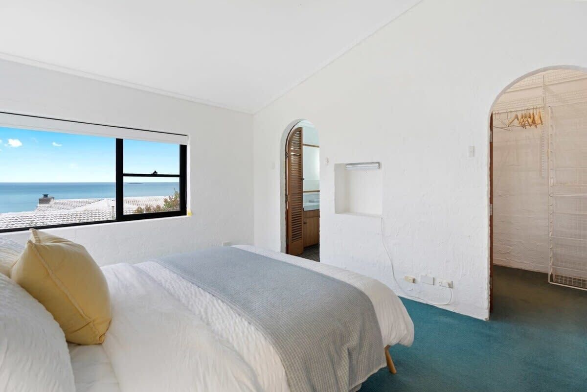 Une chambre avec une grande fenêtre, un lit et une vue sur la mer.