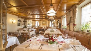 Un restaurant au décor intérieur en bois, avec de nombreuses tables dressées pour le service et des lustres suspendus au plafond.