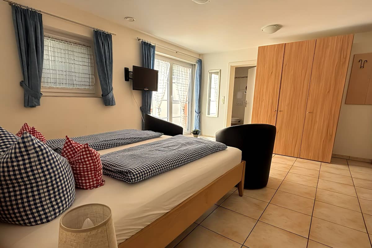 Een slaapkamer met een bed, een televisie, een kledingkast en een stoel.