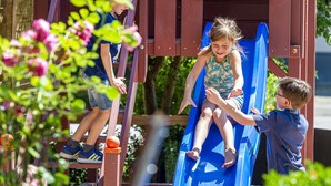 Une aire de jeux avec un toboggan bleu et des éléments d’escalade.