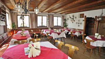Un restaurante con varias mesas preparadas para comer, vigas de madera en el techo y una variedad de decoraciones en las paredes, incluyendo cornamentas.