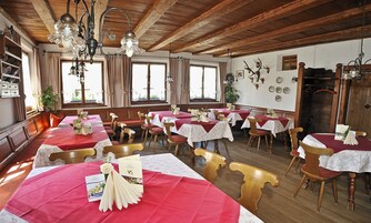 Un restaurante con varias mesas preparadas para comer, vigas de madera en el techo y una variedad de decoraciones en las paredes, incluyendo cornamentas.