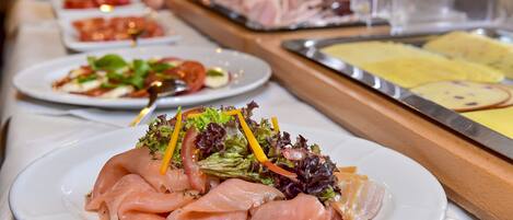 A buffet with various dishes including smoked salmon, salads, and other prepared foods.
