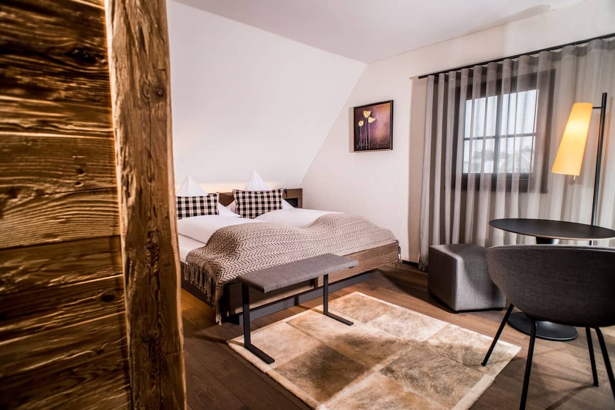 Een moderne hotelkamer met een bed, een bankje, een bureau en een stoel.