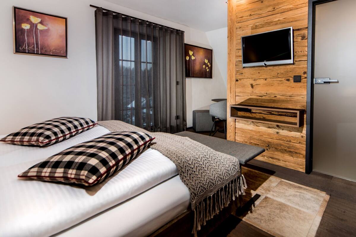 Een moderne hotelkamer met een groot bed, een televisie bevestigd aan een houten muur en een schuifdeur.