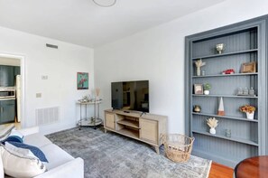 Una sala de estar moderna con televisor, sofá, mesa de centro y estantería.