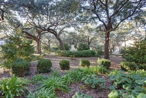 Un parque con árboles maduros, una estatua y arbustos bien cuidados.