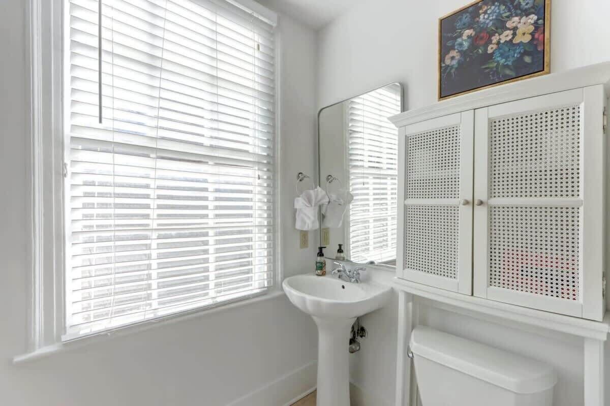 A bathroom with a white sink, a mirror, and a toilet.
