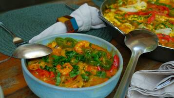 A bowl of seafood stew with a spoon and a ladle on a table.