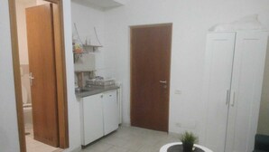 A compact kitchen with white cabinets, a small countertop, and a potted plant on a round table. - A room close to Colosseum (Roma)