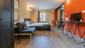 Una camera da letto moderna con un letto, un divano e un'area studio con televisione e computer.