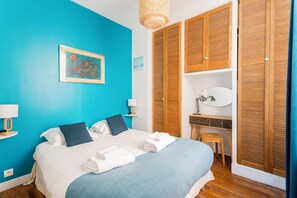 A bedroom with a bed, a desk, and a wardrobe.