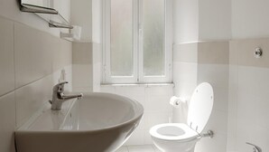 A bathroom with a large vessel sink, a toilet, and a window. - Studio 3 at the Colosseum (Roma)