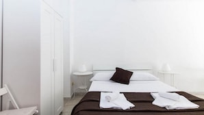 A minimalist hotel room with a bed, two bedside tables, and a wardrobe. - Studio 3 at the Colosseum (Roma)
