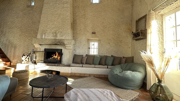 A rustic interior with a stone fireplace, a high ceiling, and a cozy seating area. - Logement Paisible - Mas Sogusthenna (Mons)